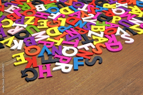 Random English Wooden Multicolored Letters On The Brown Wood Bac