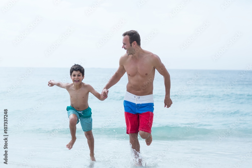 Father and son holding hands while running at beach Father and son holding hands while running at beach