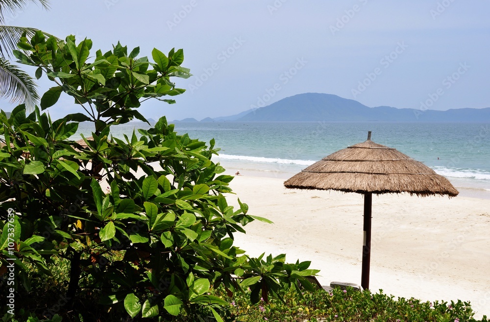Beach umbrella made of palm leaves on the background of the beach of Doc let, Vietnam