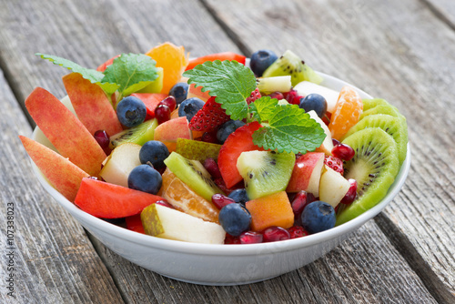 Fruit and berry salad on wooden table, close-up