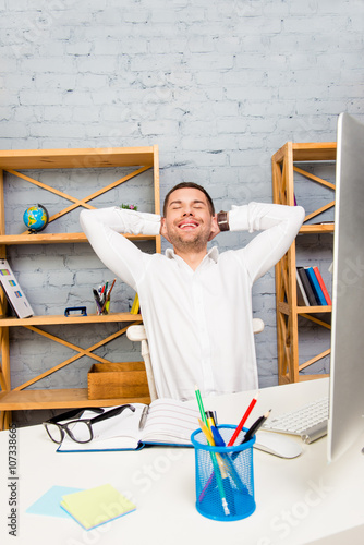 Handsome happy office worker having break and relaxing after wor photo