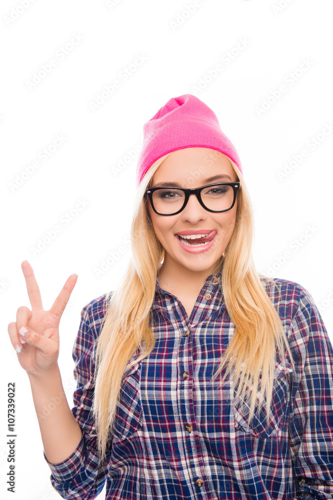 Happy girl in cap and glasses gesturing with two fingers and sho Happy girl in cap and glasses gesturing with two fingers and sho