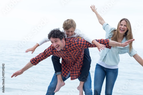 Cheerful family at sea shore against sky