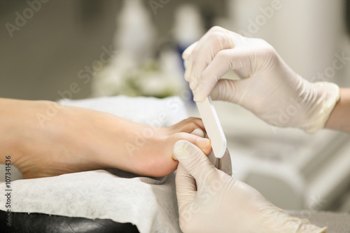 Close-up pedicure process of the big toe in spa salon. Professional work pedicure masters. © belyjmishka