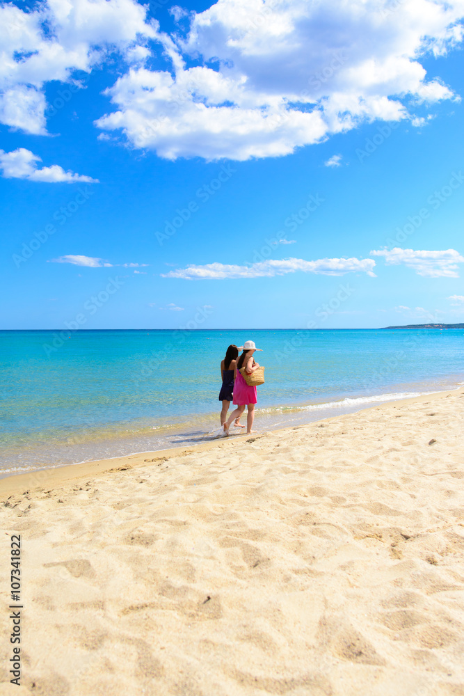Mother and daughter walking on the beach, tropical sea background