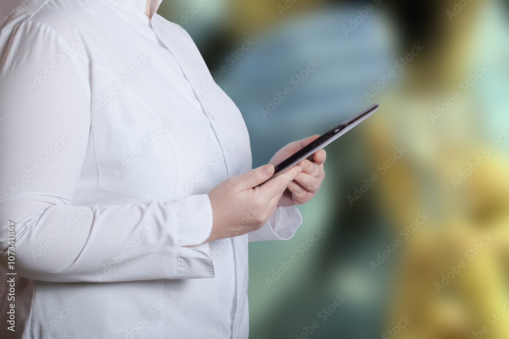 A woman in a white uniform robe with electronic device in her ha A woman in a white uniform robe with electronic device in her ha
