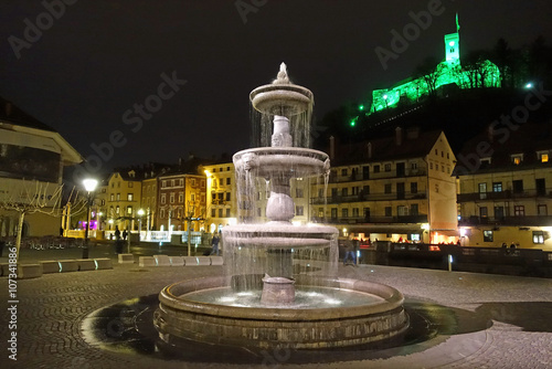 Platz "Novi trg" in Ljubjana bei Nacht, Blick auf Brunnen und Burg