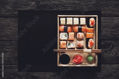 Set of sushi maki and rolls at black rustic wood.