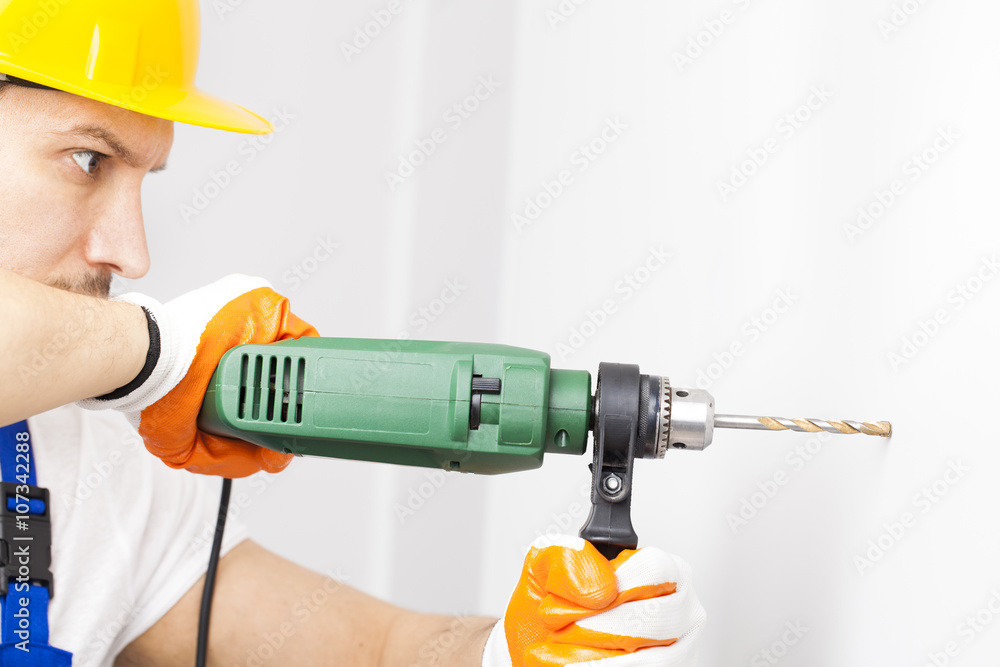 Young man drilling hole in wall Young man drilling hole in wall