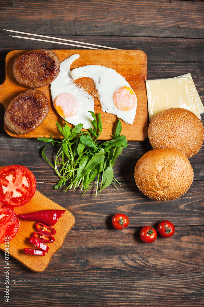 Ingredients for cheeseburgers on a dark wooden background Ingredients for cheeseburgers on a dark wooden background