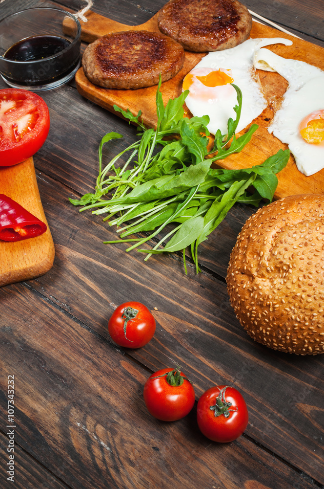 Ingredients for cheeseburgers on a dark wooden background Ingredients for cheeseburgers on a dark wooden background