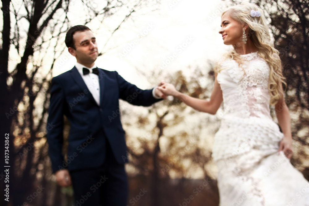blonde bride and brunette groom walking in autumn park blonde bride and brunette groom walking in autumn park