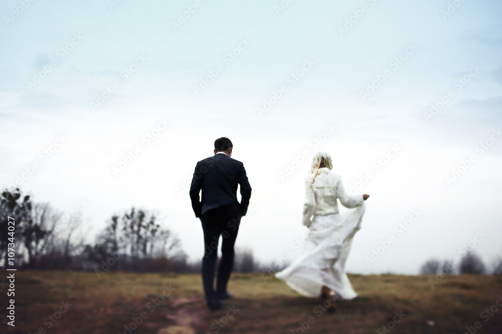 blonde bride and brunette groom walking in autumn park blonde bride and brunette groom walking in autumn park