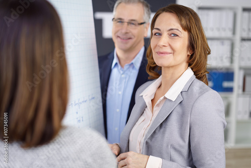 erfolgreiche ältere geschäftsfrau arbeitet zusammen mit kollegen am flipchart