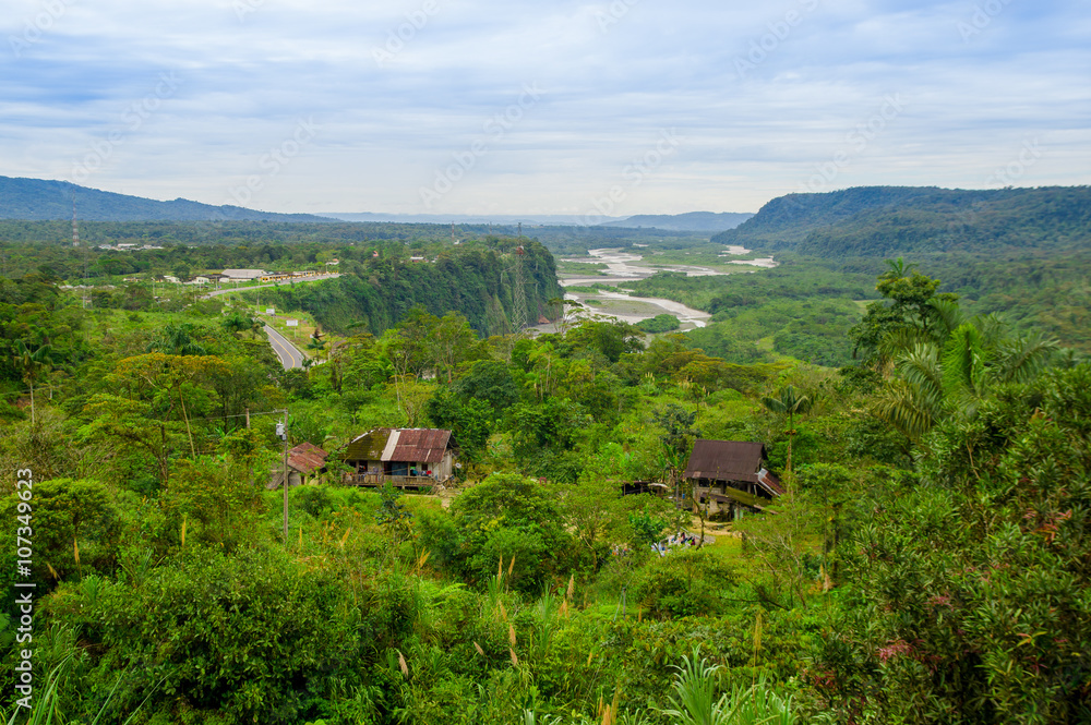 Fantastic overview of amazon jungle valley with river and waterfalls in the distance, some simple small houses located sorrounded by forest