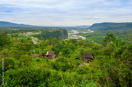 Fantastic overview of amazon jungle valley with river and waterfalls in the distance  some simple small houses located sorrounded by forest