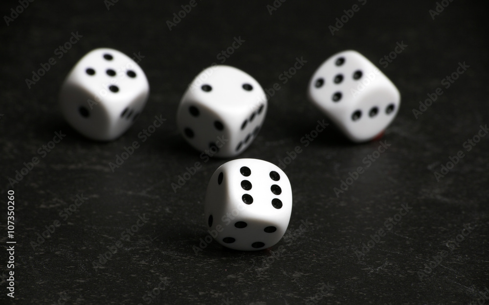 Four white and black dice on a black table Four white and black dice on a black table