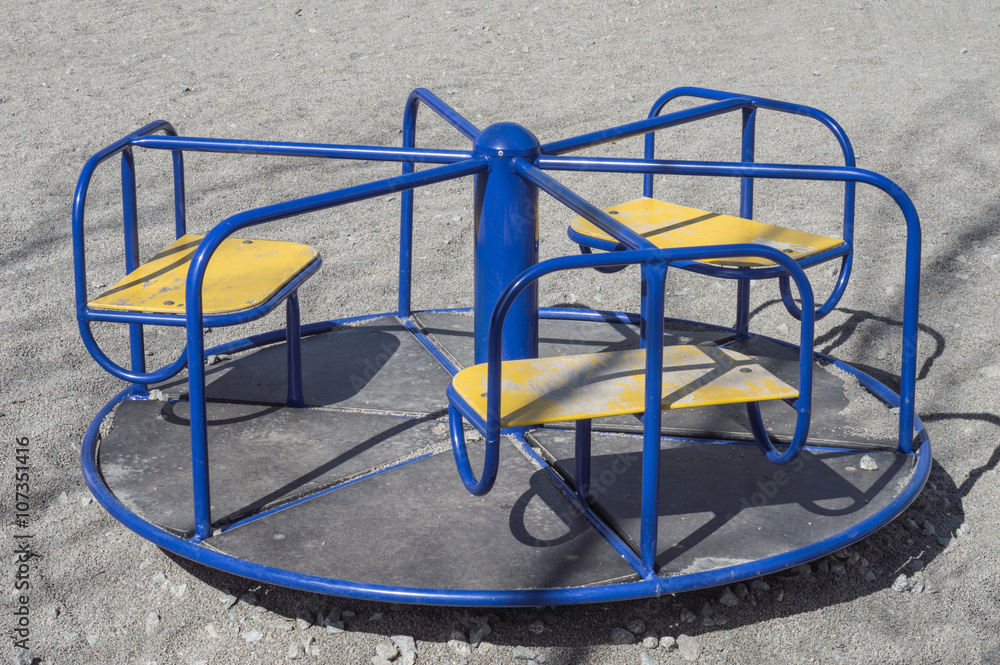 Empty children's roundabout (merry-go-round) on the playground on the crashed stone background Empty children's roundabout (merry-go-round) on the playground on the crashed stone background
