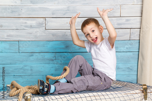 Photos little boy sitting on the box, lifting his hands up rejoices