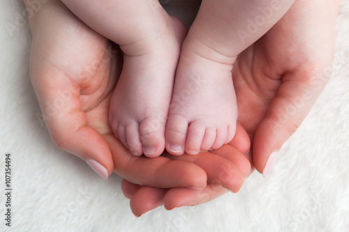 Newborn baby feet in mother's hands. Child care, feeling safe, protect.
