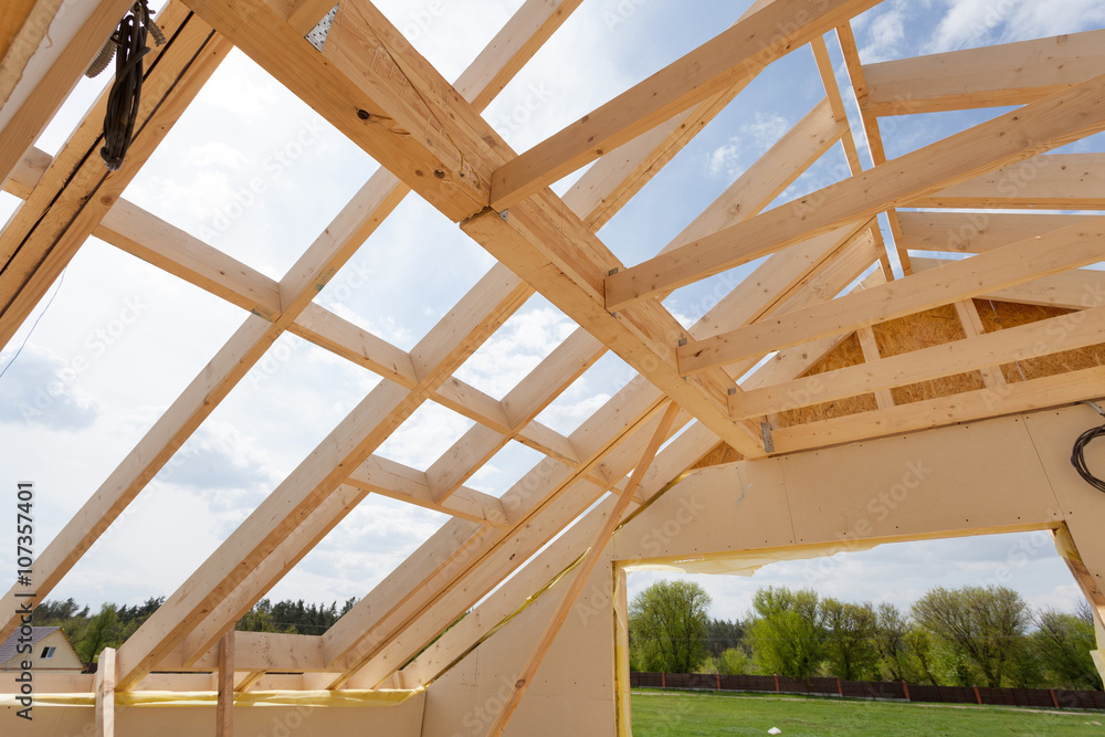 Obraz premium New residential construction home framing against a blue sky. Roofing construction. Wooden construction