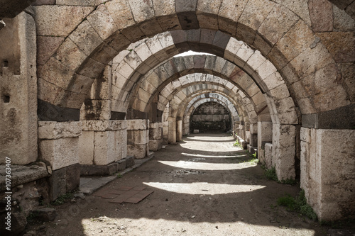 Empty stone corridor with arcs and columns © evannovostro
