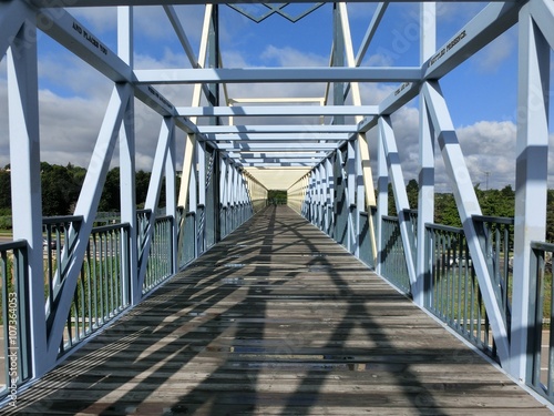 Metal girder bridge pathway centered with shadows - landscape color photo