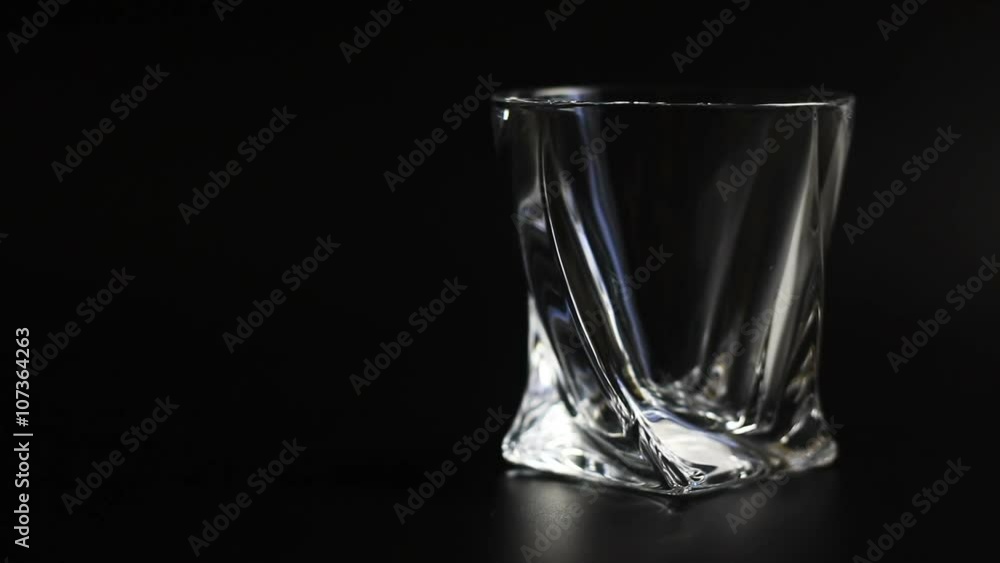 Whiskey being poured into a glass against black background. Close up. Whiskey being poured into a glass against black background. Close up.