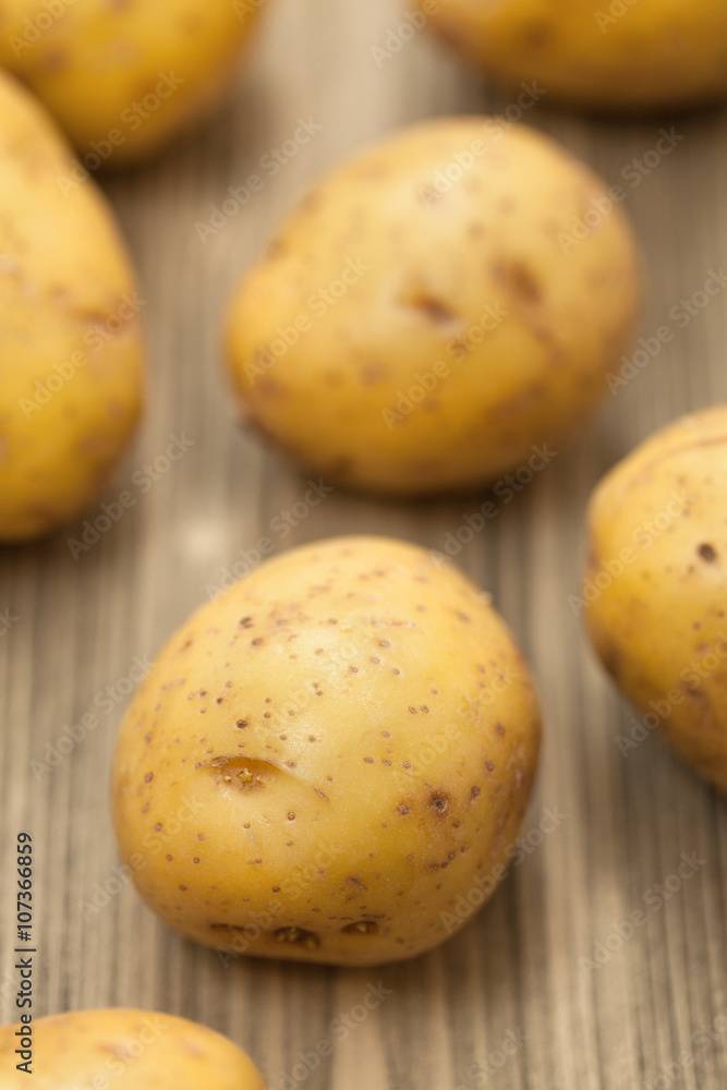 Fresh potato on wooden table, selective focus.Close-up studio ph Fresh potato on wooden table, selective focus.Close-up studio ph