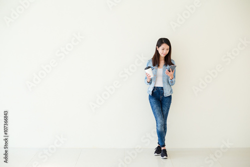 Woman look at the cellphone and hold with coffee cup