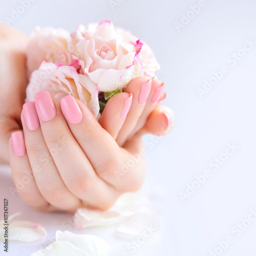 Hands of a woman with pink manicure on nails and roses