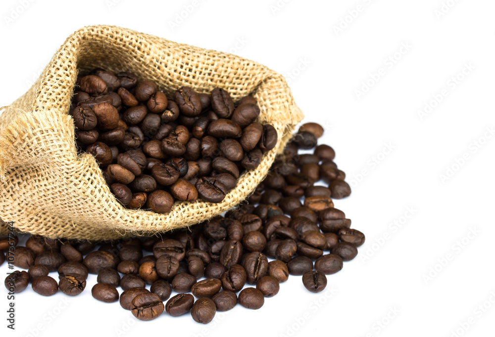 Fototapeta premium roasted coffee beans spilled on pile and in burlap sacks over wh