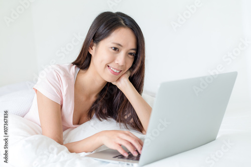 Woman using laptop computer and lying on bed