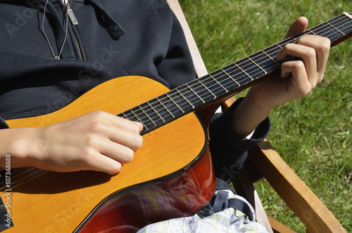 Teenage boy playing acoustic guitar outdoors
