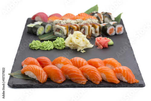Japanese cuisine. Salmon sushi nigiri and rolls on a black stone plate isolated on white background