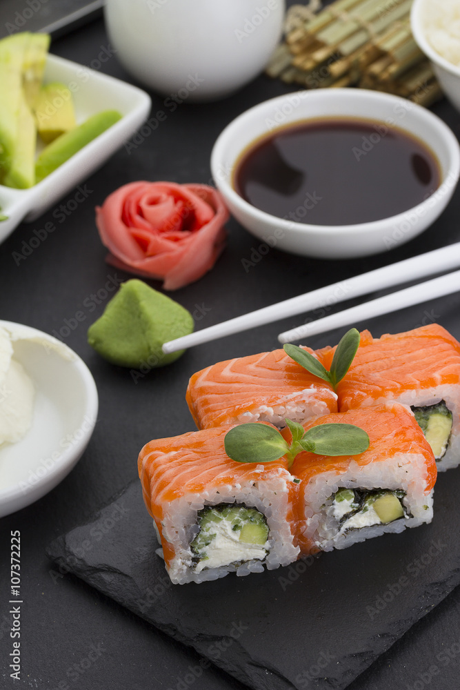 Sushi roll with fresh ingredients with ginger wasabi over black background Sushi roll with fresh ingredients with ginger wasabi over black background