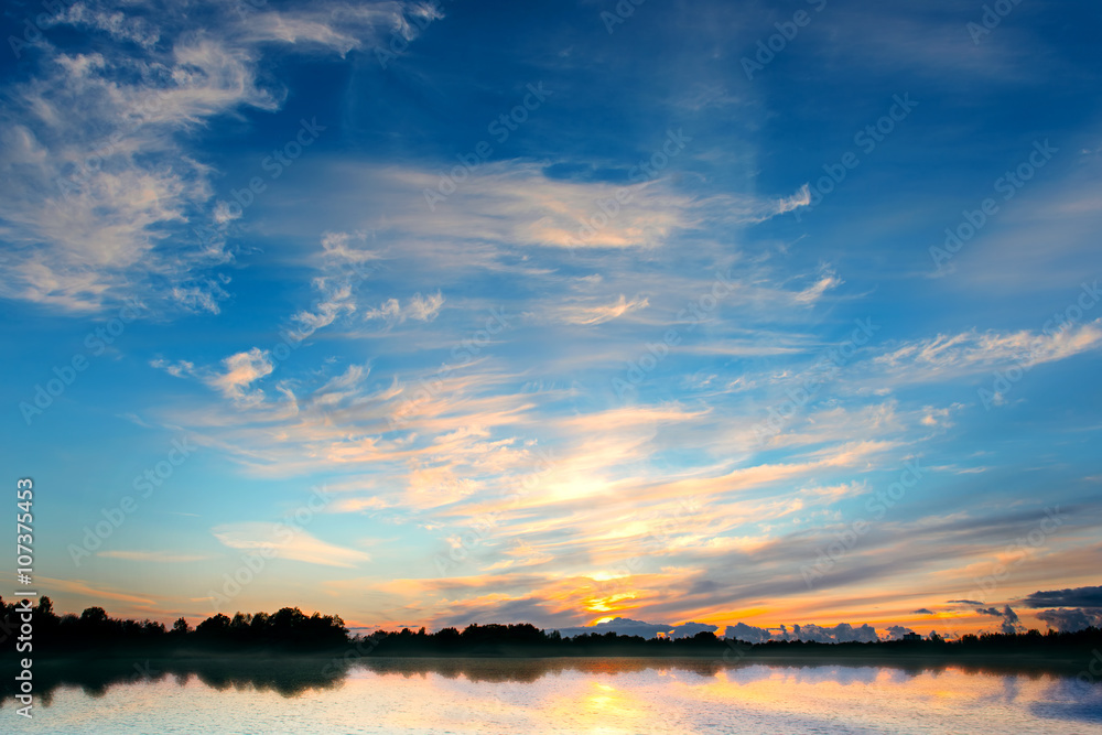 Dramatic sunset sky with forest lake and clouds Dramatic sunset sky with forest lake and clouds