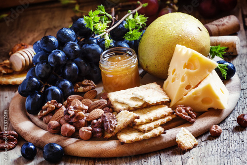 Wooden dish with appetizers to red wine, selective focus