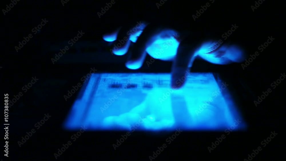Man's hand and screen close-up. Working in internet. Social networks. Reading a book on tablet PC in the dark. Switching pages. Man's hand and screen close-up. Working in internet. Social networks. Reading a book on tablet PC in the dark. Switching pages.