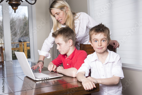 Mother with kids playing on laptop computer