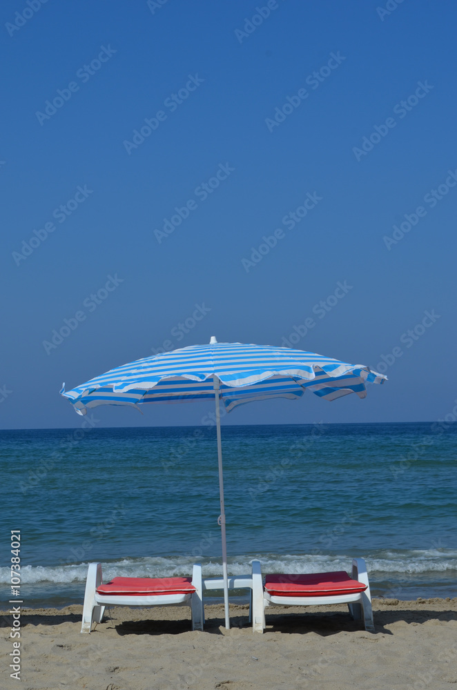 Deckchairs and colourful parasols on the beach at the Turkish Riviera close to Kusadasi