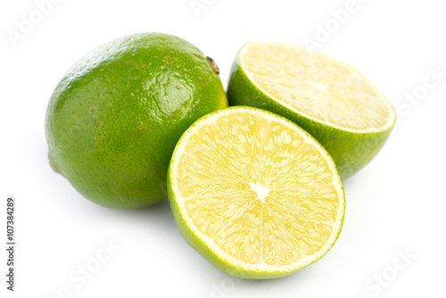 Whole and sliced fresh limes on on white, DOF