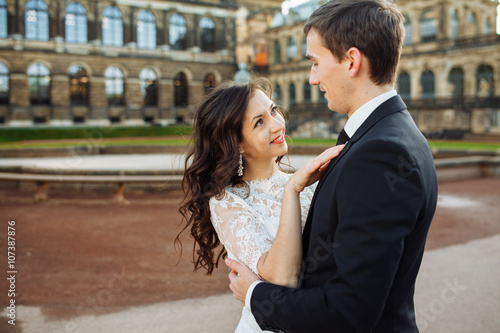 Beautiful happy wedding couple is kissing outdoors at city street background. © Maksymiv Iurii