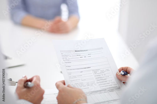 Close-up of a female doctor holding application form while consulting patient