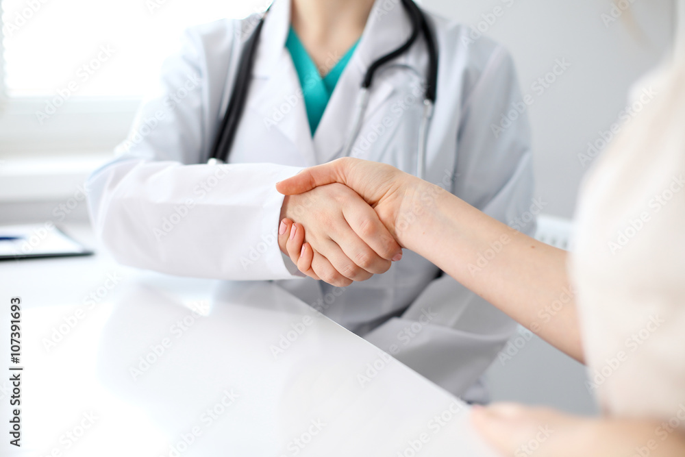 Handshake doctor and patient sitting at the table, closeup Handshake doctor and patient sitting at the table, closeup