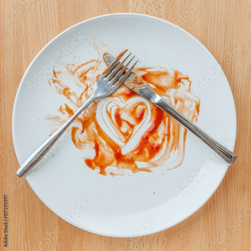 Knife and fork crossed in finish plate and heart shape ketchup,