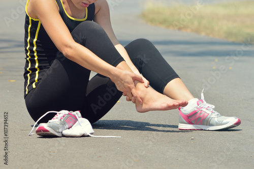  Young woman suffering from an ankle injury while exercising and photo