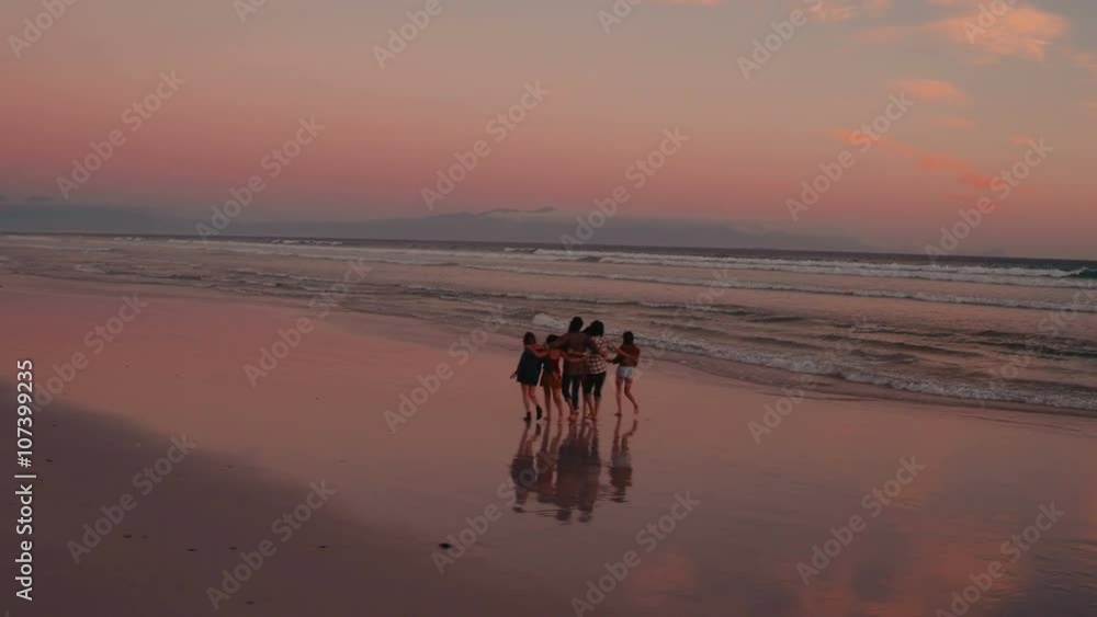 Teen friends enjoying a walk at beach on sunset Teen friends enjoying a walk at beach on sunset