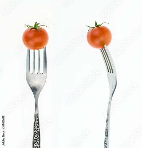 Cherry tomato on fork, front and side view, on white background.