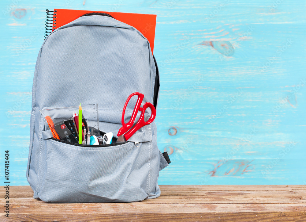 Naklejka premium Backpack with school tools on turquoise background